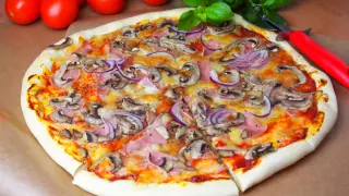 Pyszna pizza capricciosa z pieczarkami, szynką i czerwoną cebulą, gotowa do podania.