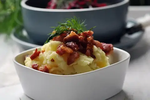Pyszna zupa z botwiny z ziemniakami, podana z chrupiącym boczkiem i koperkiem.