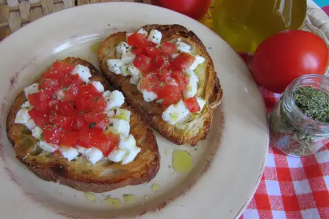 Bruschetta z pomidorami i mozzarellą: chrupiące grzanki z soczystymi pomidorami i kremową mozzarellą, posypane ziołami. Idealny przepis na szybką przekąskę.