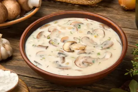 Kremowa zupa pieczarkowa, jak u babci, z kawałkami pieczarek i świeżymi ziołami.