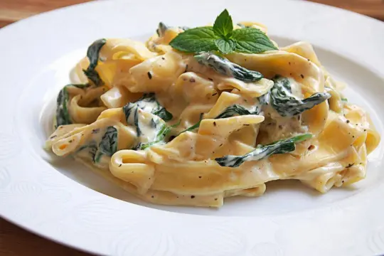 Pappardelle z szpinakiem w kremowym sosie mascarpone, udekorowane listkiem mięty. Pyszne danie, które rozpływa się w ustach.