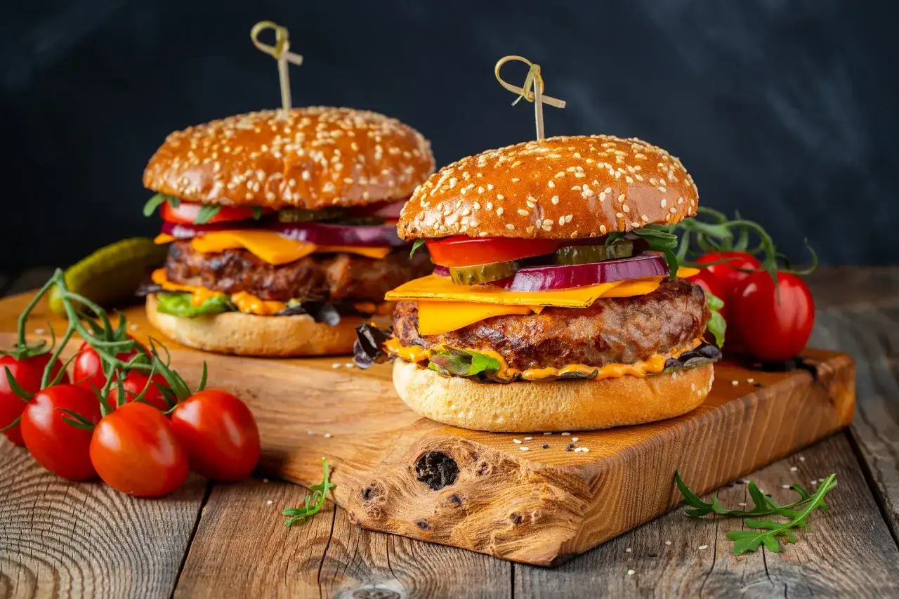 Dwa soczyste burgery z wołowiny, idealne na grilla. Idealne jakie mięso na burgera? To właśnie takie! Z serem, warzywami i piklami.