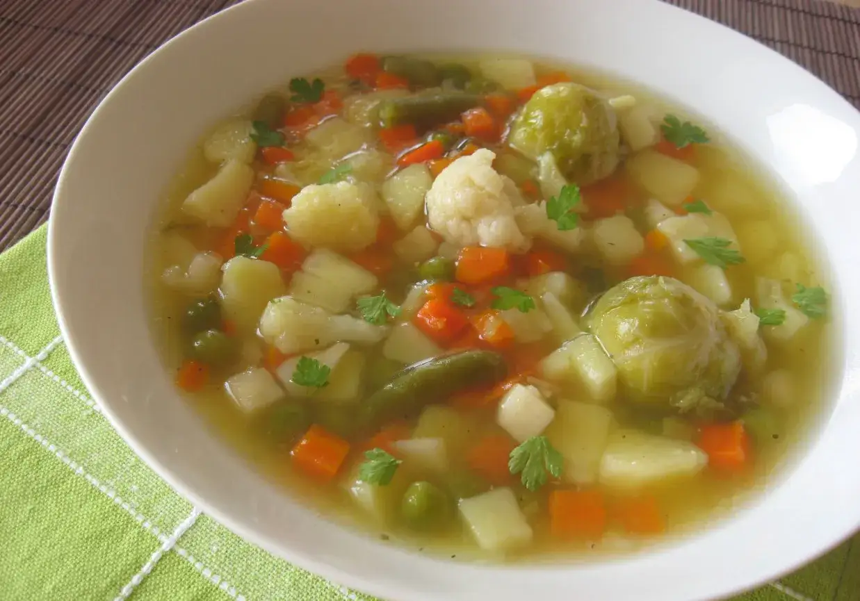 Aromaticzna, tradycyjna zupa jarzynowa z ziemniakami, marchewką, kalafiorem, fasolką i brukselką, udekorowana natką pietruszki.