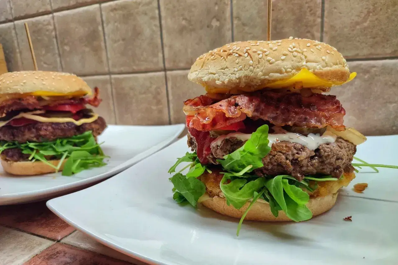 Dwa soczyste burgery z wołowiny, bekonem i rukolą. Idealne, jakie mięso na burgera wybrać, by uzyskać taki efekt.