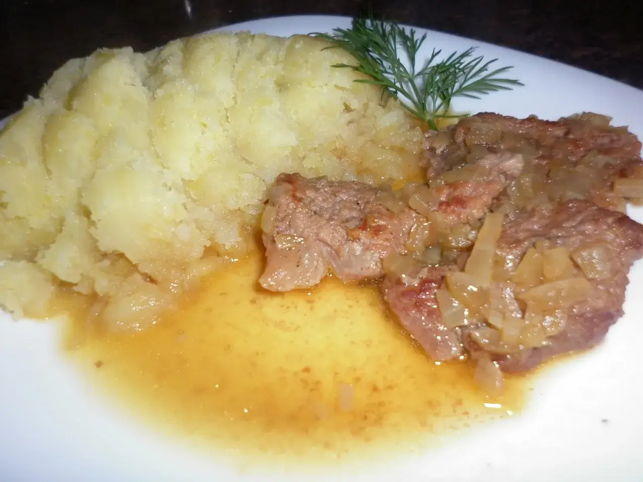 Pyszna cielęcina w sosie własnym, jak u Ani, podana z purée ziemniaczanym i gałązką koperku.