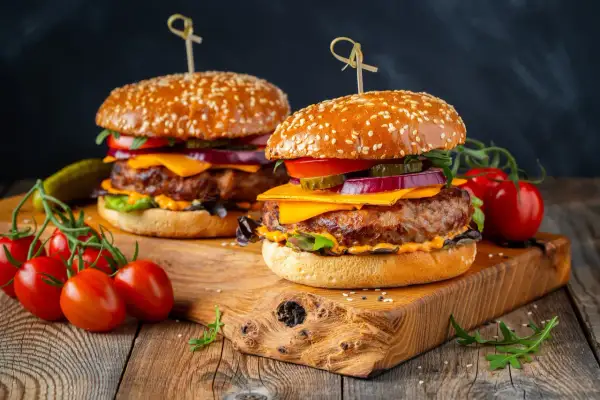 Dwa soczyste burgery z wołowiny, idealne na grilla. Idealne jakie mięso na burgera? To właśnie takie! Z serem, warzywami i piklami.